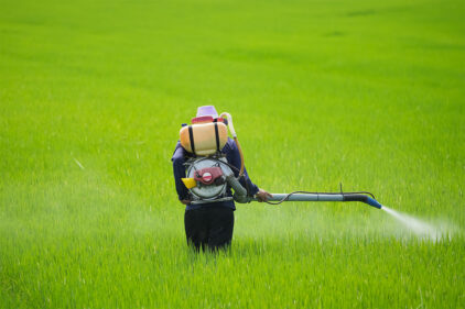 Farm Worker Spraying Field in Countryside Setting