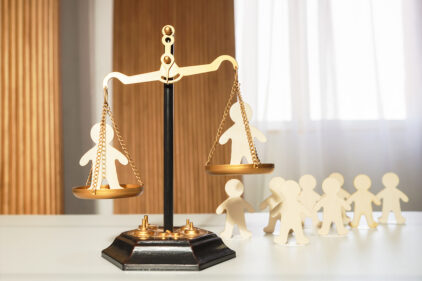 On the judge's scales, there are figures of people in each bowl, with a waiting