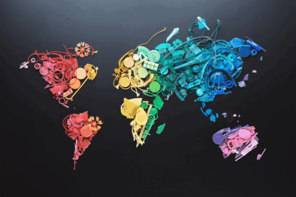 Map of the world from rainbow bright colored pieces of non-decomposable garbage collected on the beach during sea tide in Thailand